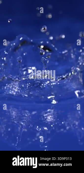 Splashes of water rise from a glass, creating sparkling droplets ...
