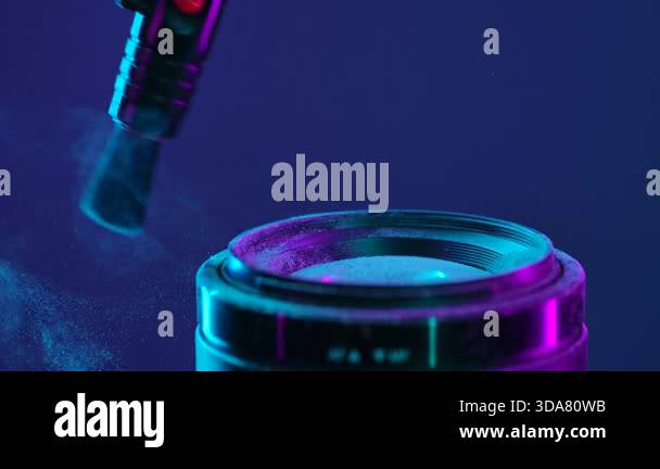 A close up of a camera lens being cleaned with a brush to remove dust ...