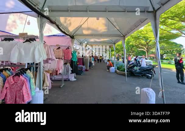 Outdoor market with colorful clothing stalls under tents, lively ...