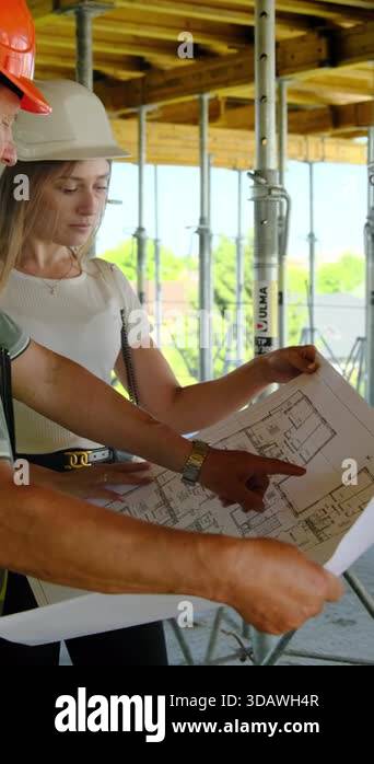 Foreman explains layout to engineer looking at floor plan. Worker ...