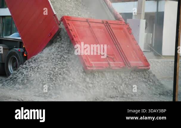 Large red tipper truck unloading a pile of gravel and crushed stone ...