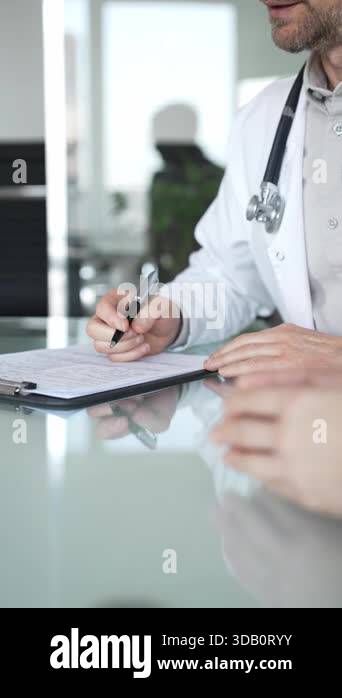 Doctors hands writing notes on a clipboard while consulting with a ...