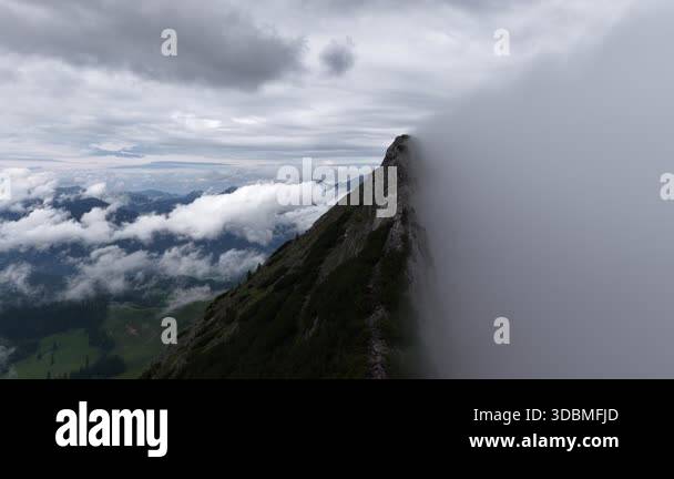 Dramatic aerial view of a steep alpine ridge with its summit swallowed ...