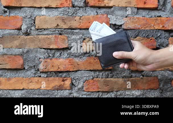 hand holding wallet showing some dollar bills stored isolated on brick ...