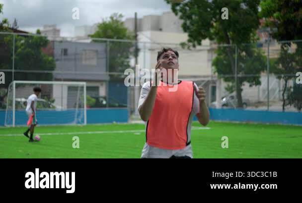 Young man doing headers on soccer field during soccer practice ...