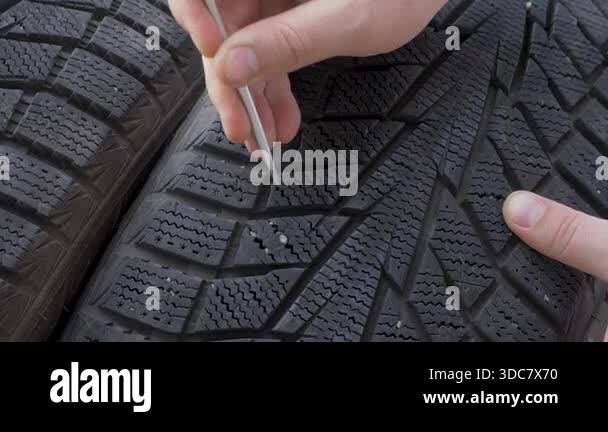 Man hand removes small stones from deep tire tread. Prepares wheel for ...