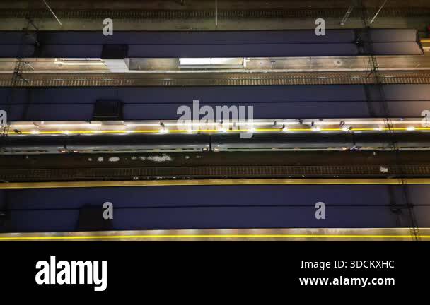 Train approaching platform at night, illuminated by overhead lights ...