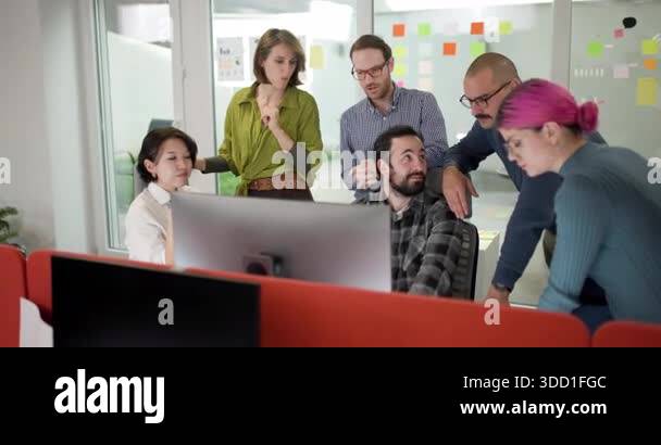A team of business professionals gathers around a computer screen to ...