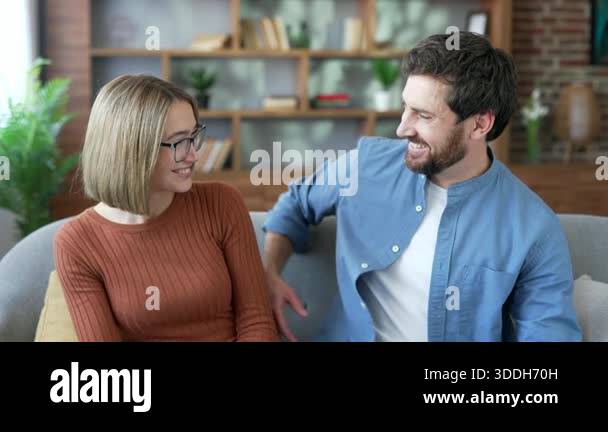 Portrait of happy married couple hugging sitting on sofa in living room ...