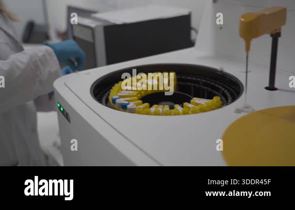 Lab technician in uniform places blood samples into automated robotic ...