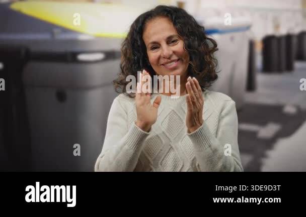 Woman clapping outdoors near a recycling container, showcasing ...