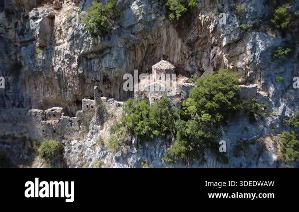 Stone walls and a ruined church emerge from a cave high in the mountain ...