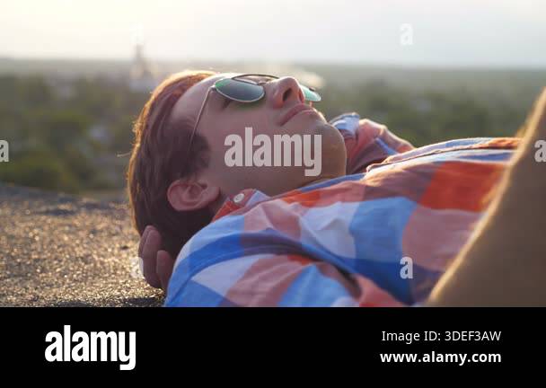 Handsome guy in sunglasses lying of the edge on rooftop of high-rise ...