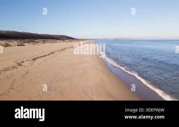 Aerial view of empty sandy beach and calm sea under clear blue sky ...