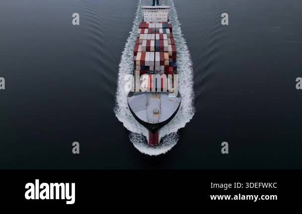 Top-down aerial view of container ship sailing through calm sea ...