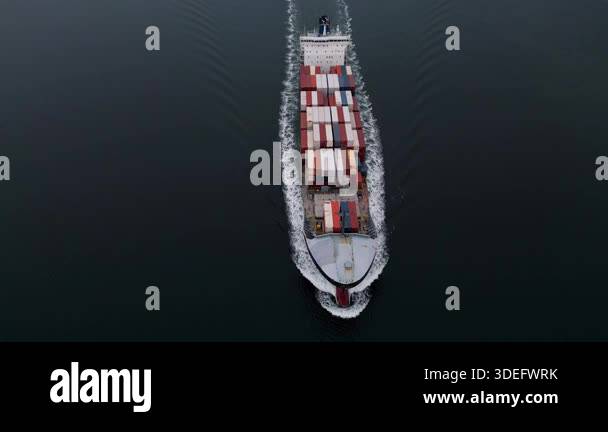 Top-down aerial view of container ship sailing through calm sea ...