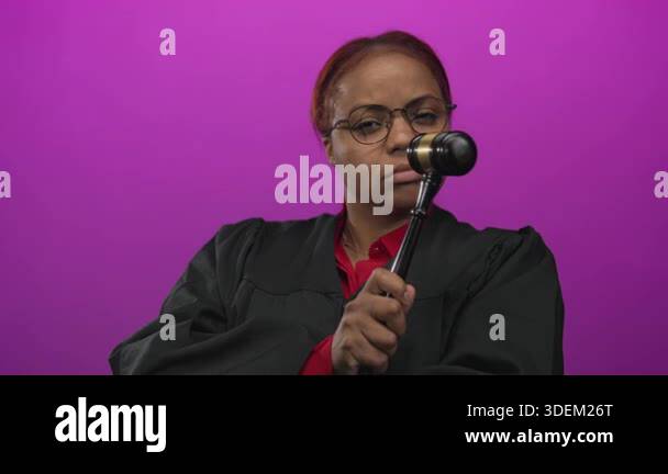 Woman in judge robe holds gavel in purple studio set with magenta ...