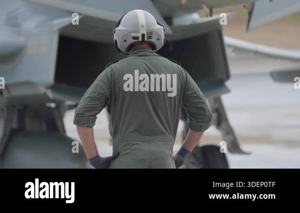 Rear view of a ground crew member in helmet and uniform standing near a ...