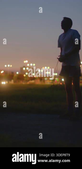 Man stretching in park at twilight, bending forward to loosen ...