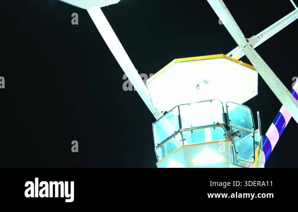 Slow motion ferris wheel at night in an amusement park. Empty wagons ...
