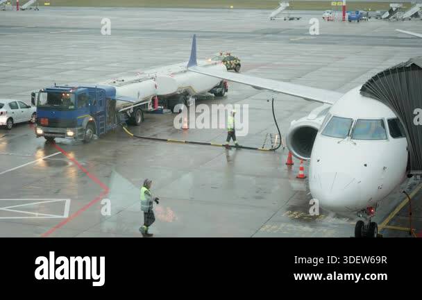 Commercial aircraft refueling process at airport apron on rainy day ...