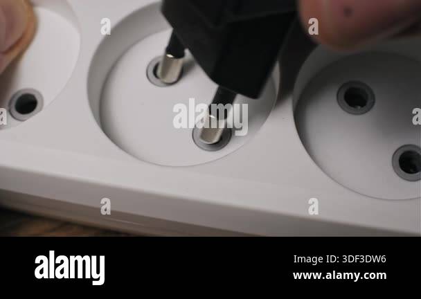 Close-up shot of a male hand inserting a black electric plug of ...