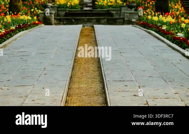 A pathway leads through a garden filled with bright flowers in spring ...