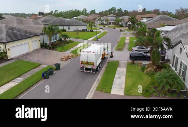 American garbage truck picking up trash bins on rural street side Stock ...