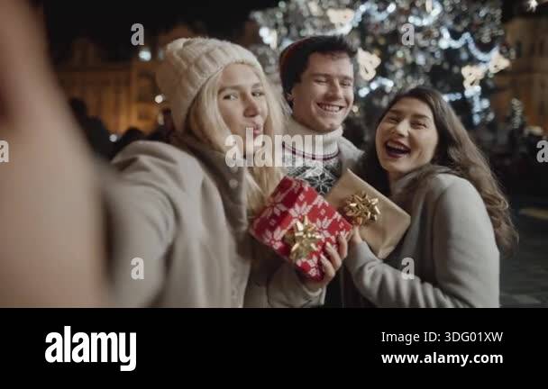 Selfie by a group of friends in front of tall christmas tree in center ...
