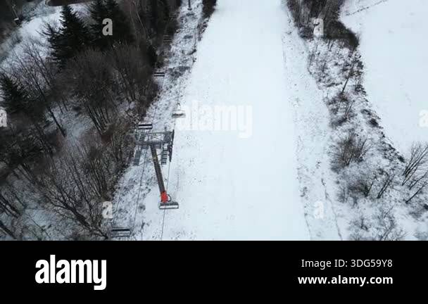 Sparse Snow Aerial view of snow-covered landscape showcasing ski lift cables ...