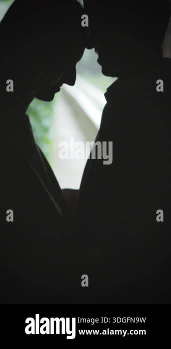 Silhouette of a loving couple sharing a tender moment in a dimly lit ...