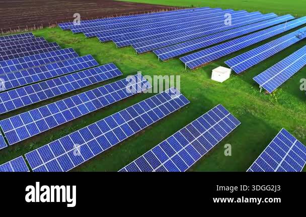 Rows of solar panels cover green fields, capturing sunlight to generate ...