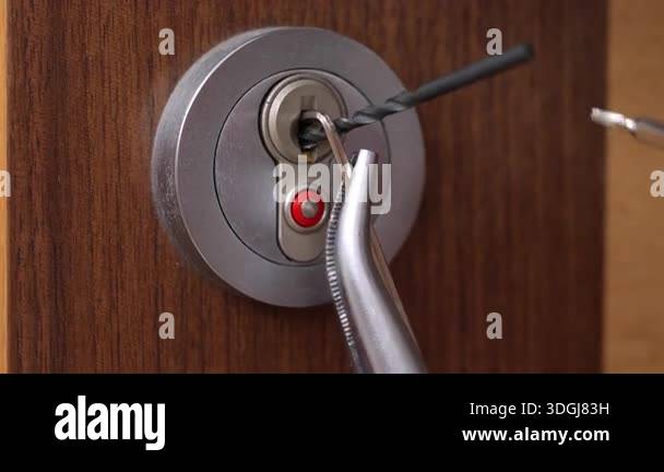 Close-up of a metal door lock with tools inserted into the keyhole ...