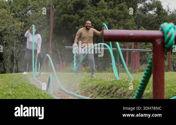Young couple performing battle rope exercises together, creating waves ...