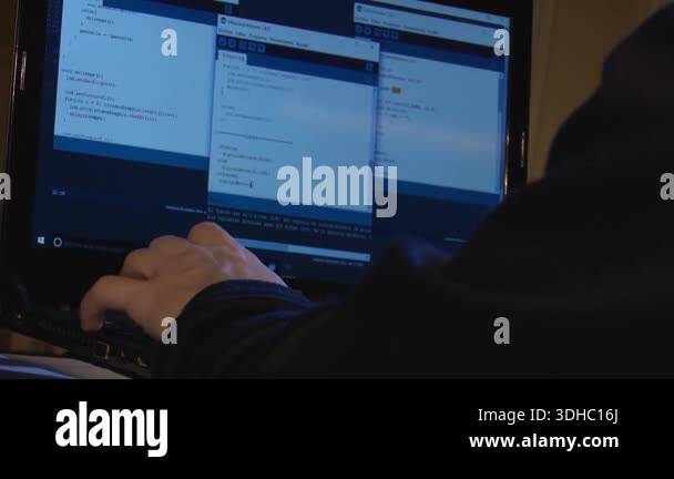 Hands typing on a laptop in dark blue lighting. Cinematic close-up of a ...