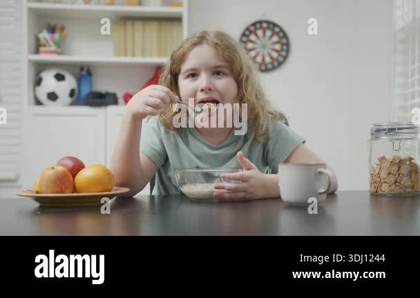 Child Eating Routine Child eating at home kitchen. Kid sitting at table eating meal. Child ...
