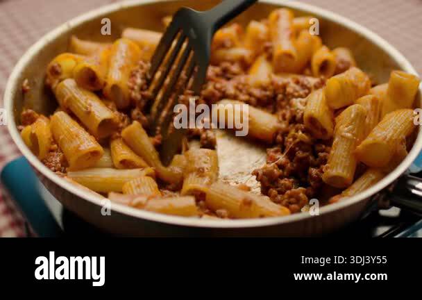 Delicious pasta Bolognese cooking in a frying pan. The dish features ...