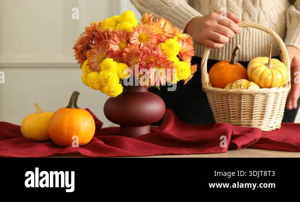 Woman creating beautiful autumn composition with flowers and pumpkins ...