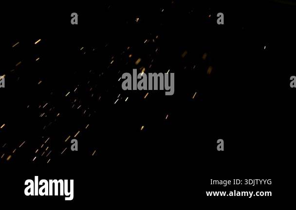 Cinematic shot of bright glowing sparks and embers flying across a ...