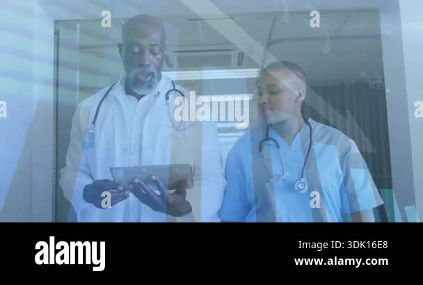 Senior doctor and nurse walking corridor while tapping tablet viewing ...
