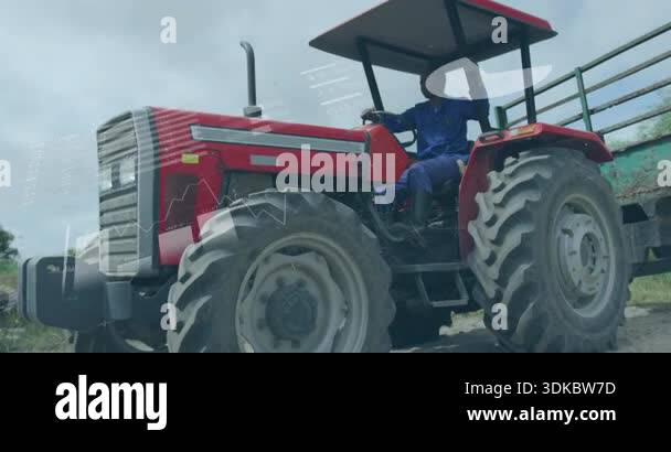 Driver starting red farming tractor towing green trailer, while data ...