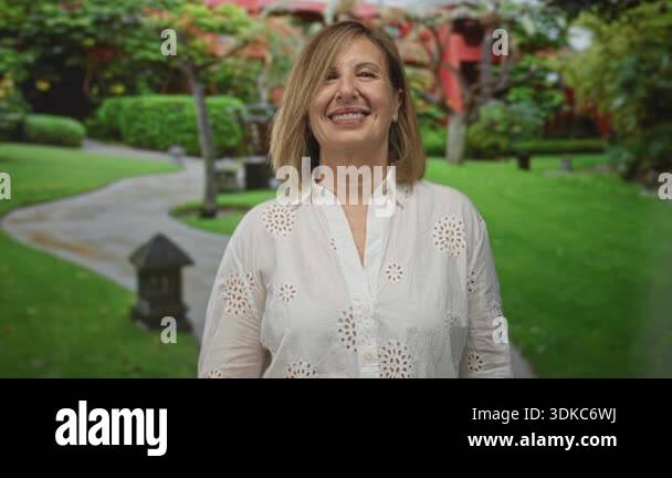Woman wearing white eyelet blouse holds ok sign with hand on winding ...