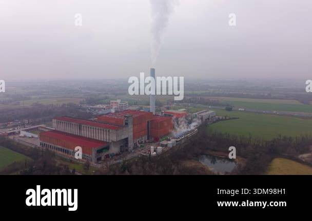 Large industrial facility with a tall chimney releasing smoke ...
