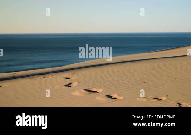 Person walks along golden sand dune above Namibia Coast, leaving ...