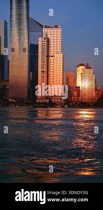 Sunset view of New York City buildings along the waterfront. Tall ...