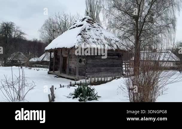 Traditional wooden hut with a thatched roof covered with snow in a ...