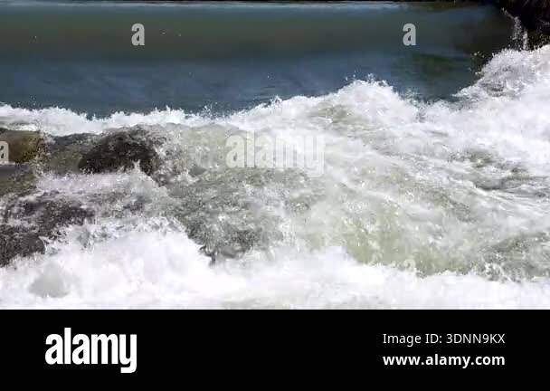 Slow motion footage of the river flowing through the stones and the ...