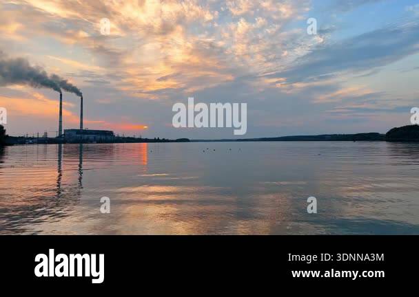 Sunset over river showing industrial area in the distance with smoke ...