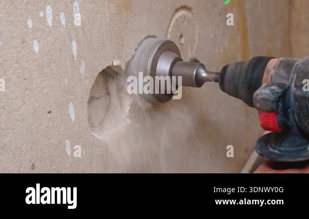 Electric drill with hole, cutting a round hole in plaster wall, forming ...
