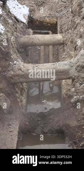 Excavation trench repairing an old district heating pipeline in winter ...